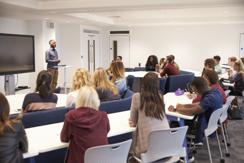 Students attending interactive workshops in a classroom setting with a mentor explaining cloud and DevOps concepts.